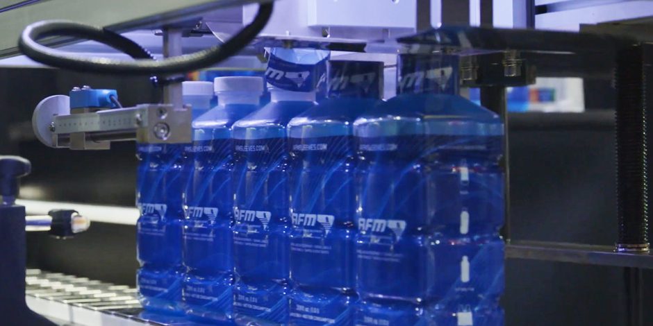 Rows of blue plastic bottles on CH-100 Tamper Evident Band Applicator