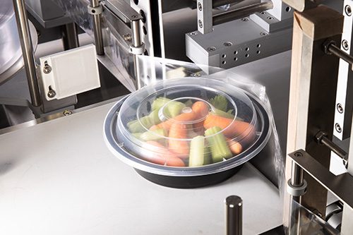 Vegetables in a container wrapped with a shrink band entering the AutoBandit